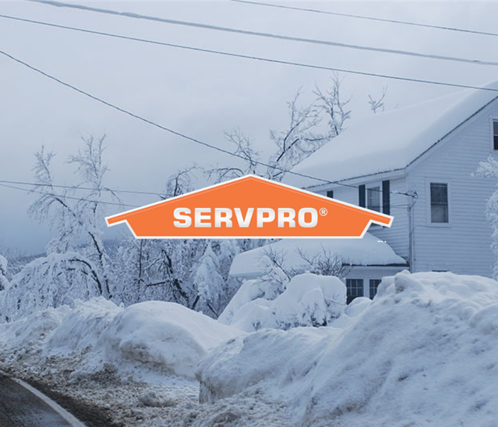 SERVPRO logo in front of tall piles of snow and house with snow on roof